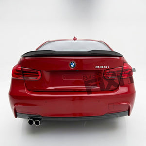 Rear view of a red BMW 3301 model car with a black trunk spoiler, on a white studio background.
